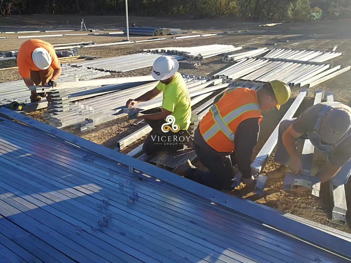Workers preparing and assembling steel structural elements laid out on the greenhouse construction site